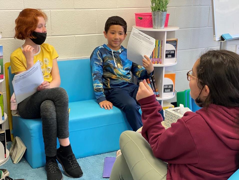 Students sitting in a group discussing a book.